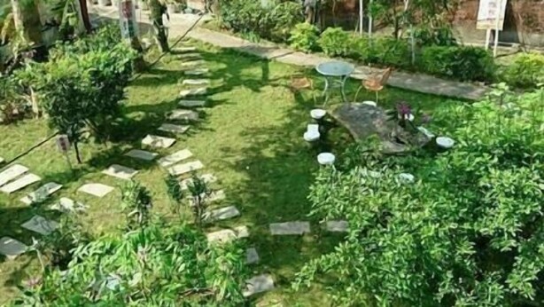 Ein Garten mit einem Kiesweg, Bäumen und einem kleinen Tisch.