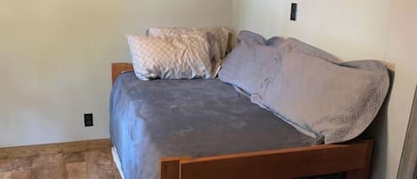 A small, single-bed room with a wooden headboard and a grey bedspread.