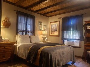 A bedroom with a bed, bedside table, lamp, and a window with curtains.