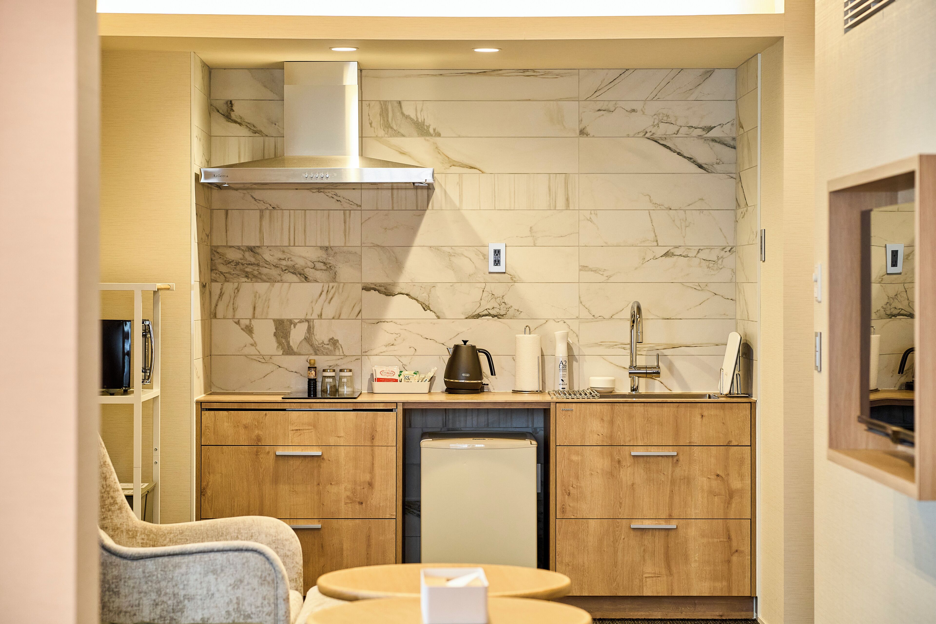 A compact kitchen with marble backsplash, wooden cabinets, and a small refrigerator.