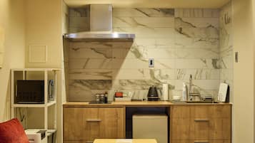 Une cuisine compacte équipée d’une cuisinière, d’un four à micro-ondes et d’un réfrigérateur intégrés.