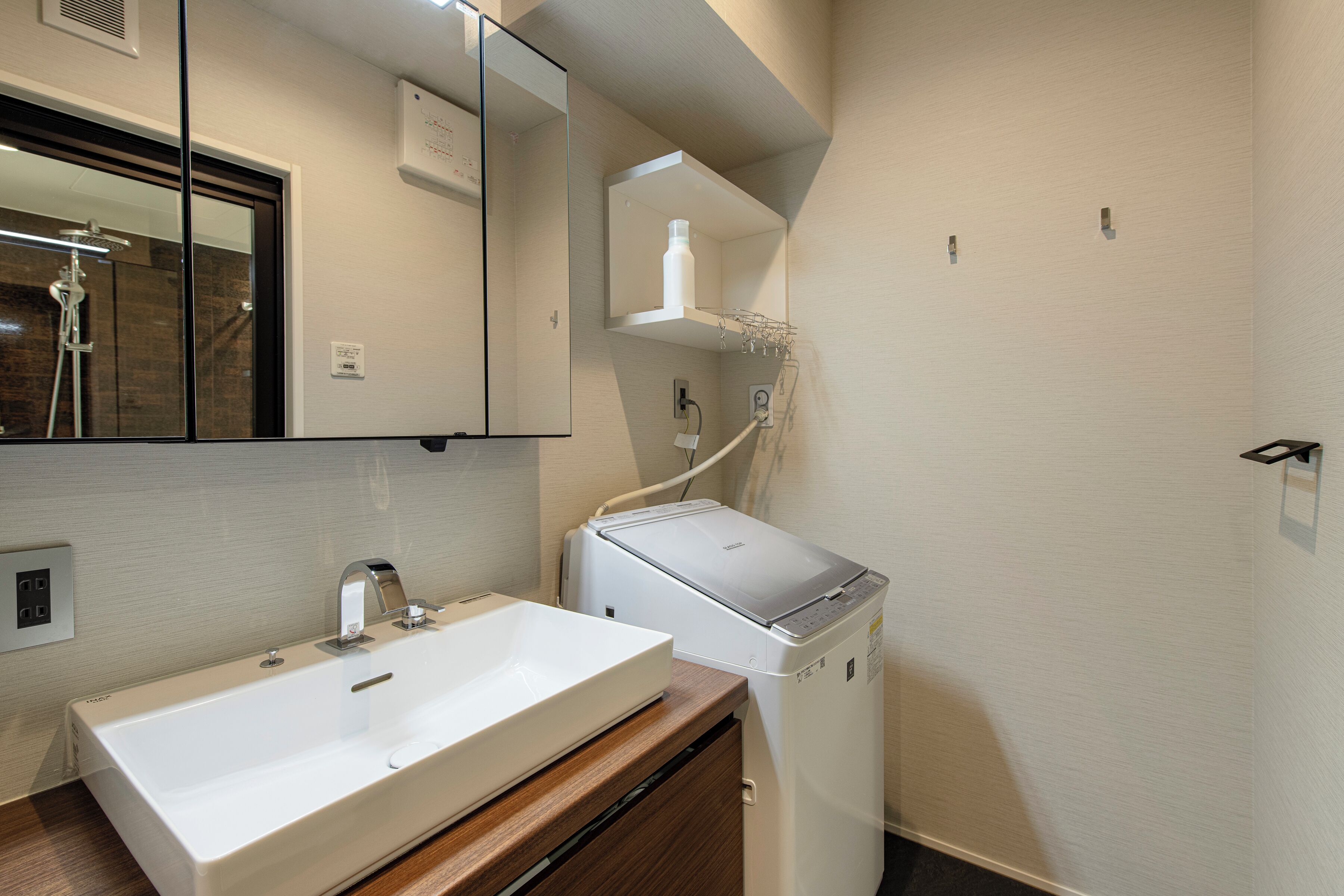 Un baño con lavamanos blanco, espejo y lavadora blanca.