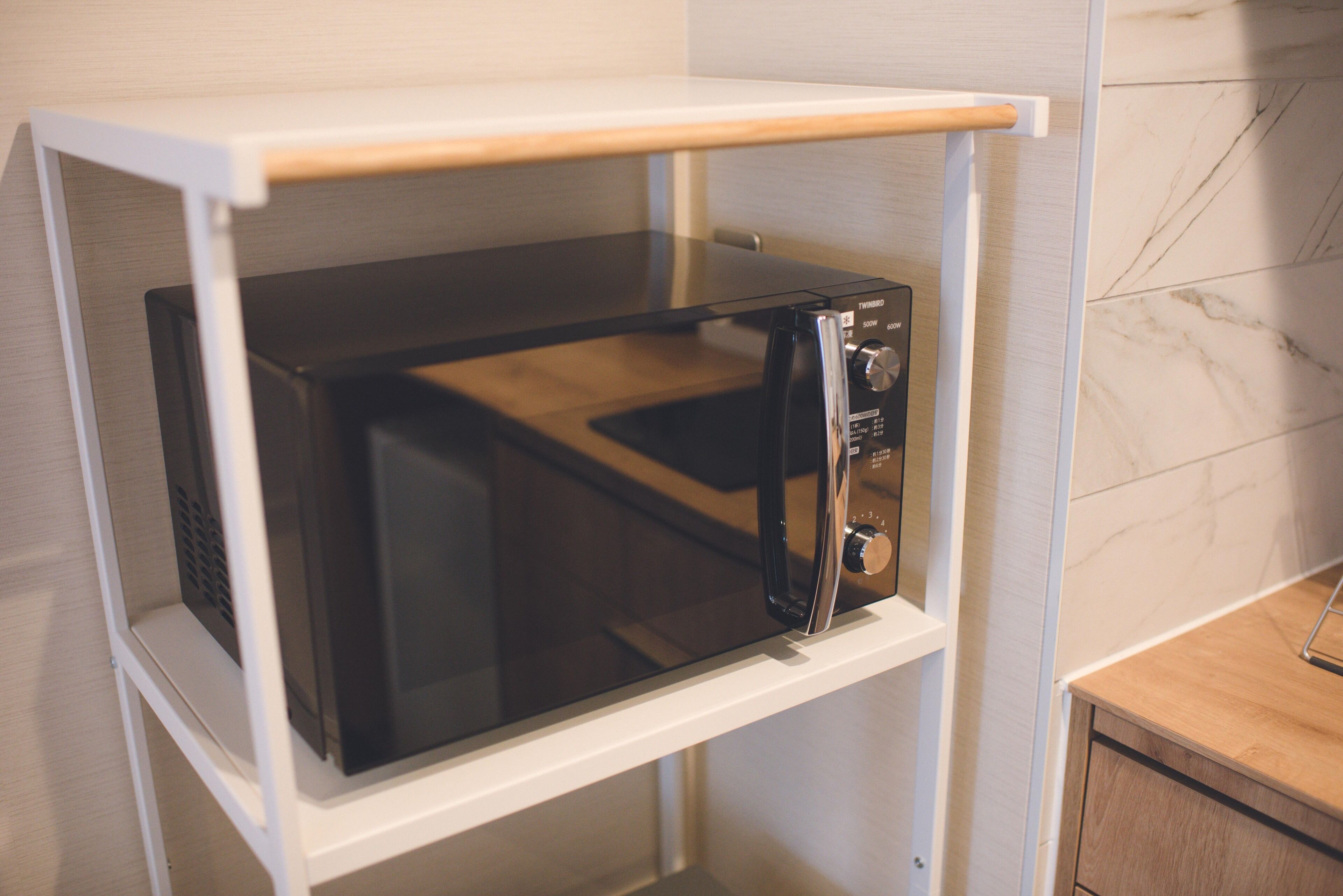 Een magnetron bevestigd aan een witte plank met een houten aanrecht eronder.
