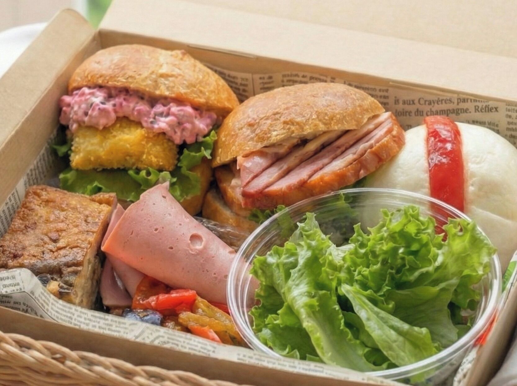 A box containing a sandwich, a small container of salad, and some vegetables.
