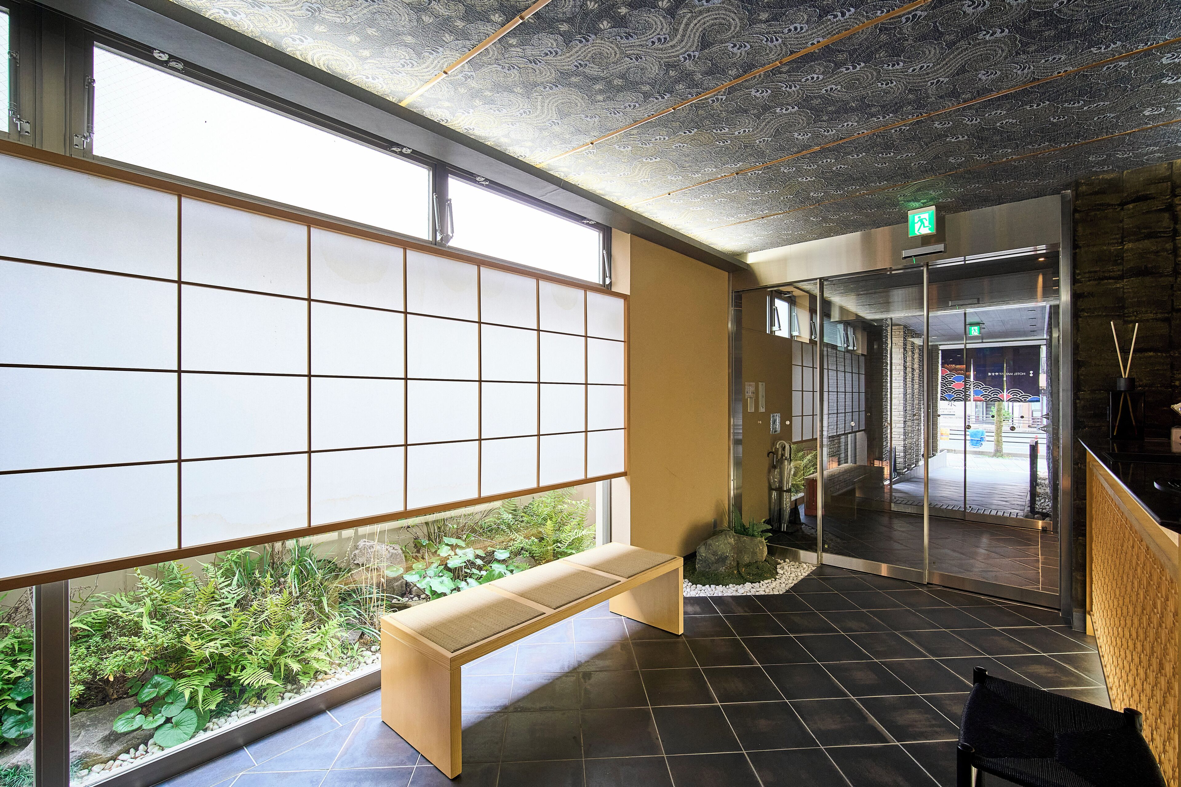 Uma área de recepção com um banco de madeira, janelas amplas e vista para o verde lá fora.