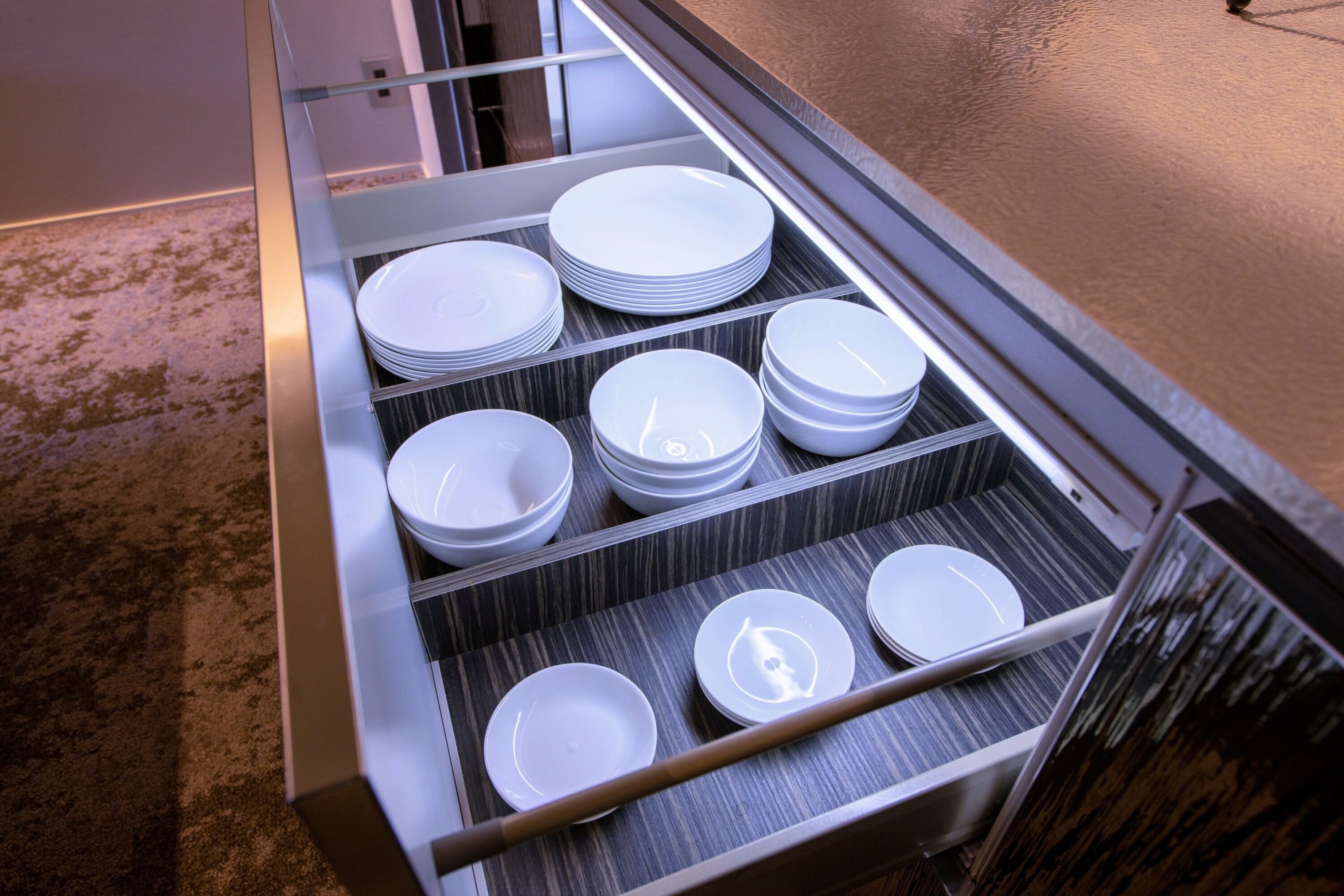 A drawer with neatly stacked white plates and bowls, indicating a well-organized kitchen area.