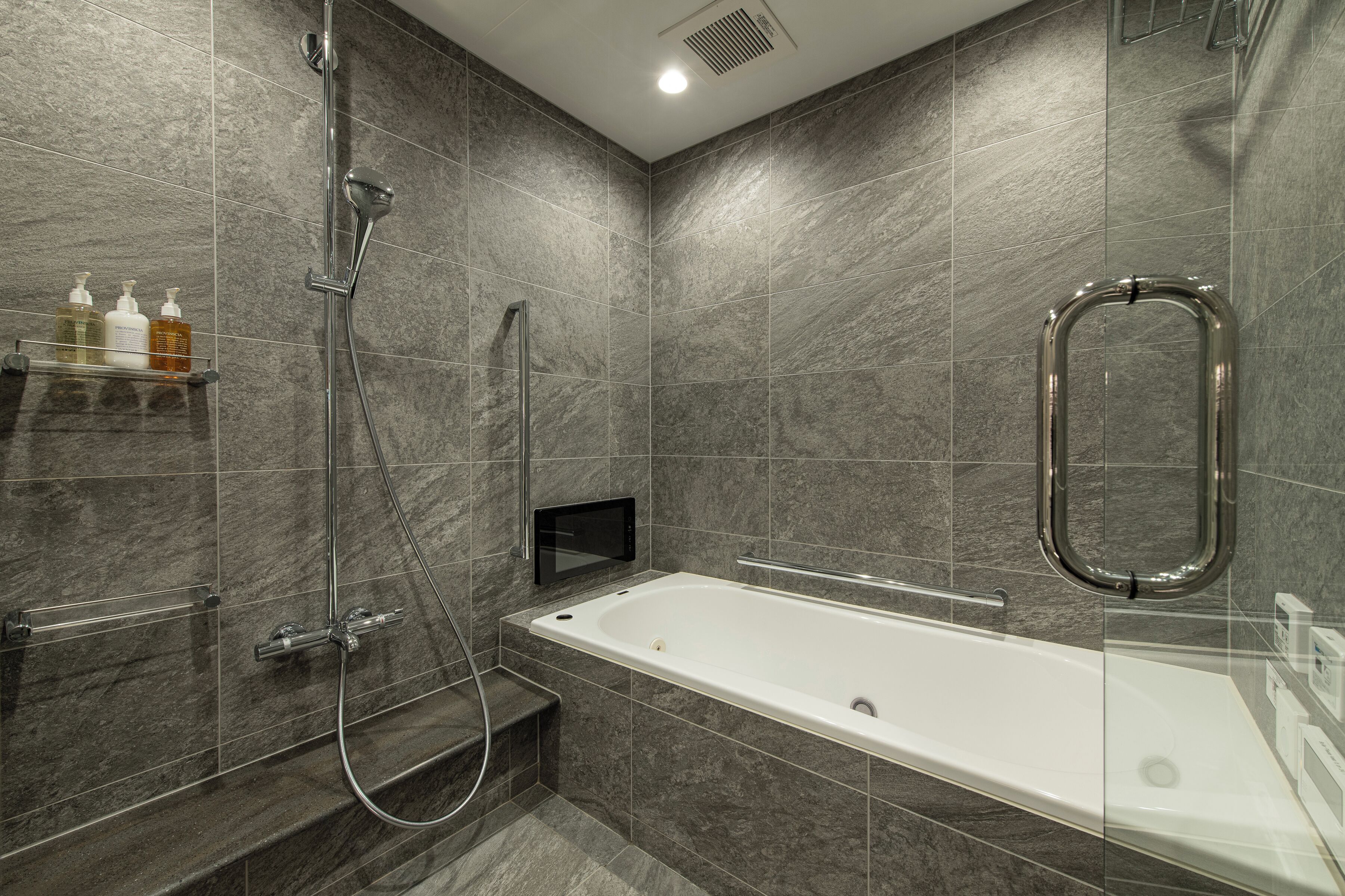 Un baño moderno con bañera, ducha y barras de apoyo.