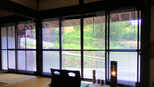 A tatami mat room with a tatami mat sofa, a small table, and a candle. - Kumano Kodo Nagano Guesthouse (Tanabe)
