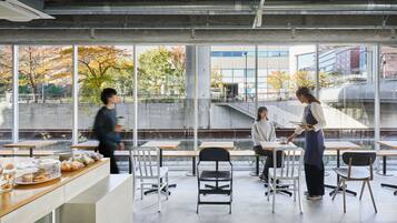 An indoor space with large windows, a counter with food items, and several tables and chairs.