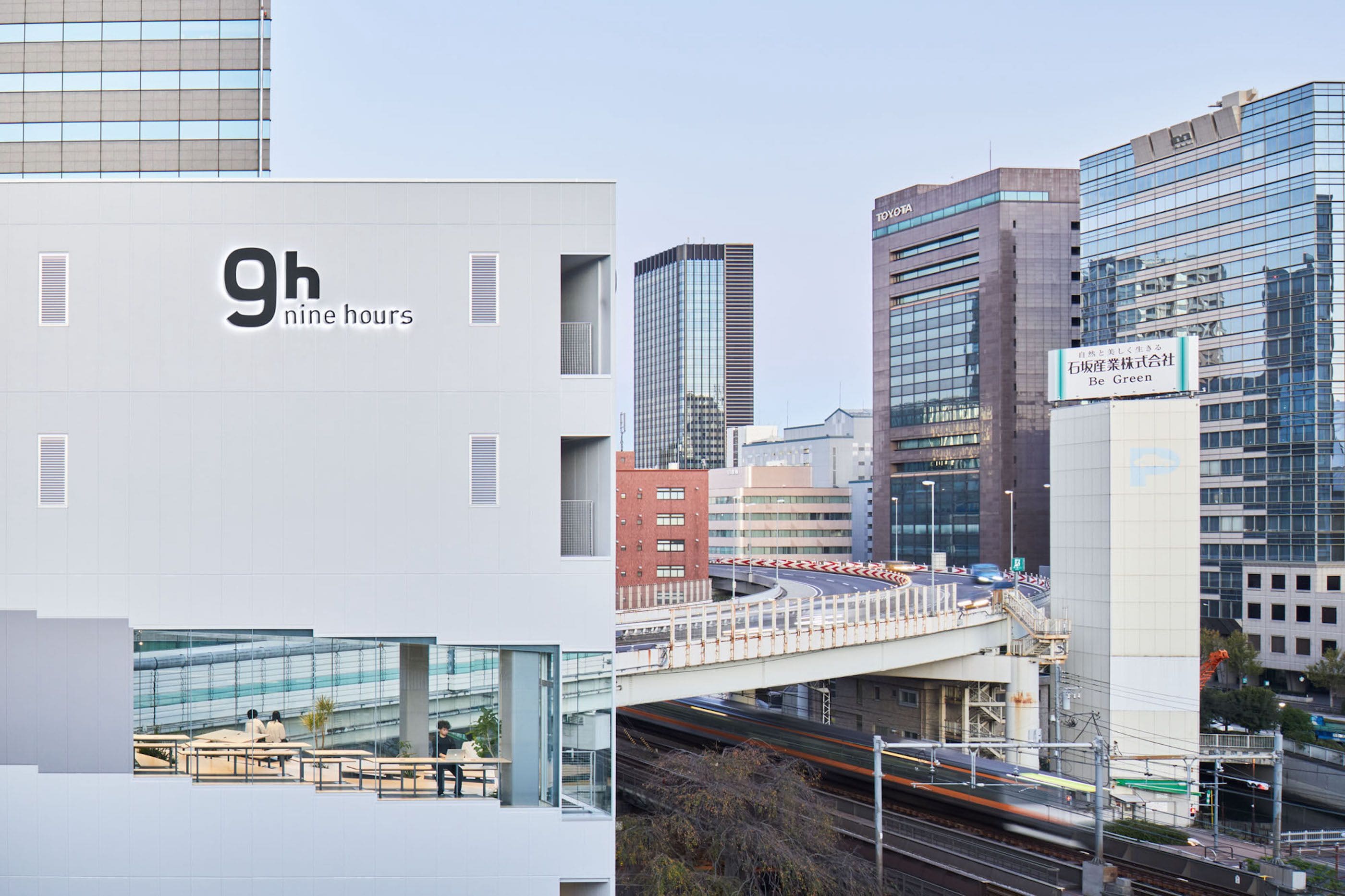 A modern building with a sign reading '9h nine hours' and another sign for 'Be Green'.