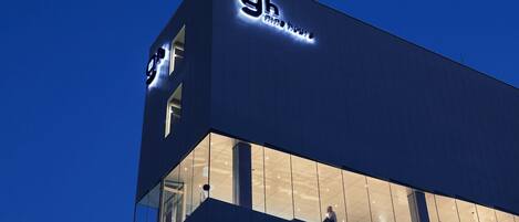 Un edificio moderno con insegna illuminata che riporta '9h Nineteen'.