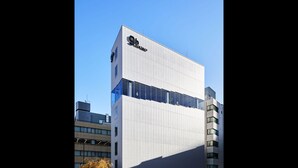 Un edificio moderno con un llamativo letrero '9h', grandes ventanales y techo plano.