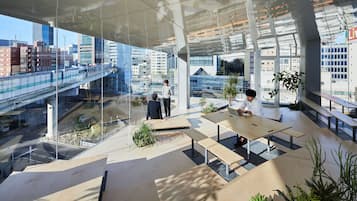 An indoor space with large windows, modern furniture, and a view of a cityscape with a bridge.