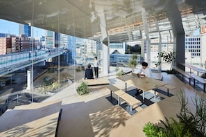 An indoor space with large windows, modern furniture, and a view of a cityscape with a bridge. - 9h nine hours Suidobashi (Tokyo)