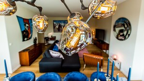 A modern living room with a unique glass chandelier, a black sofa, and a wooden coffee table.