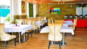 A restaurant with wooden flooring, white tables, and beige chairs. - Omega Gardens Hotel (Karatina)