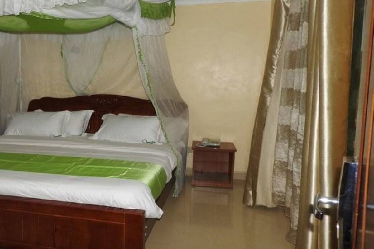 Ein Bett mit Baldachin, ein Nachttisch und eine Tür in einem Hotelzimmer.