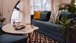 A living room with a blue sofa, a white coffee table, and a patterned rug. - Basco Central Apartment Little Bay (Belgrade)