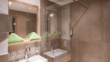 Un baño moderno con dos lavamanos, ducha con cerramiento de vidrio y un espejo grande.