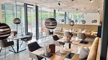 Uma sala de jantar moderna com mesas, cadeiras e luminárias esféricas penduradas.