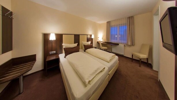 Habitación de hotel con cama doble, escritorio, silla y televisión.