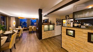A modern restaurant with a stone bar, wooden flooring, and a view of the city at night. - Hotel-Restaurant Sonneneck (Dornstetten)