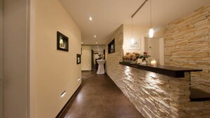 A hallway with a stone wall, recessed lighting, and framed pictures on the wall. - Hotel-Restaurant Sonneneck (Dornstetten)