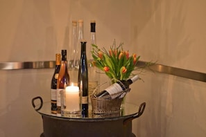 Una mesa de cristal con botellas, una vela y un jarrón de tulipanes.