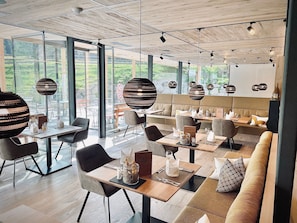 Un comedor moderno con mesas, sillas y lámparas esféricas colgantes.