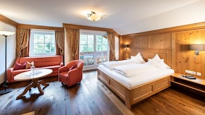 Una habitación de hotel con una cama, un sofá, una silla, una mesa y un ventanal.