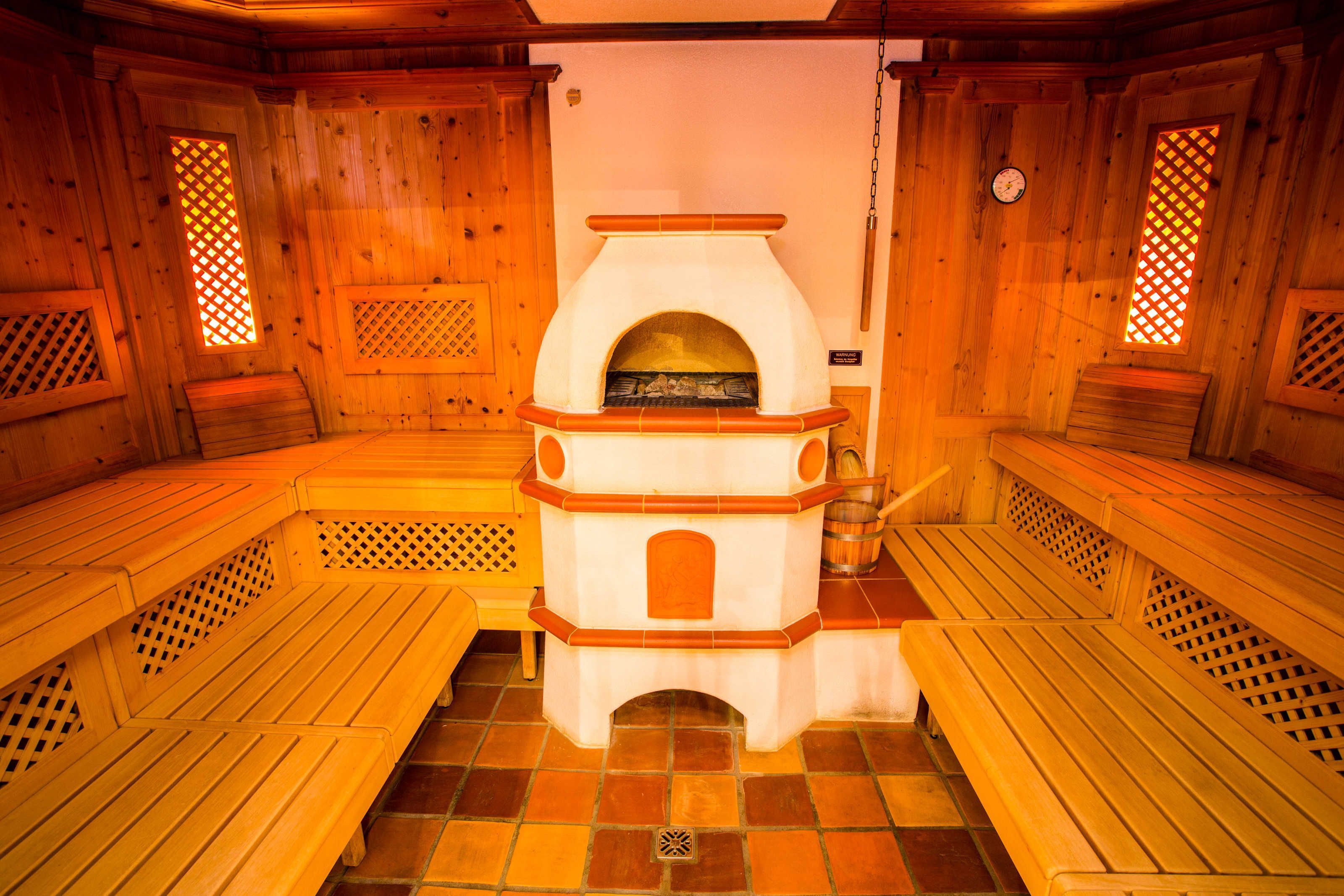 Sauna, jossa on puiset penkit ja keskeisellä paikalla sijaitseva takka.