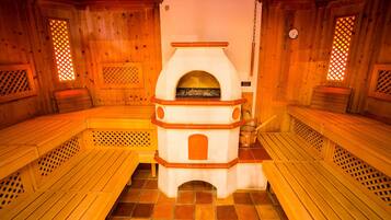 Sauna, jossa on puiset penkit ja keskeisellä paikalla sijaitseva takka.