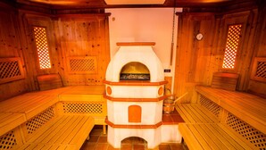 Una sauna con bancos de madera y una chimenea central.
