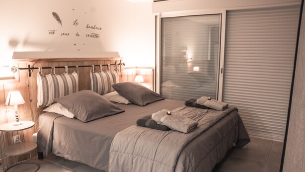 Une chambre à coucher avec un lit, des oreillers, un tapis moelleux, une table de chevet avec une lampe et une armoire.