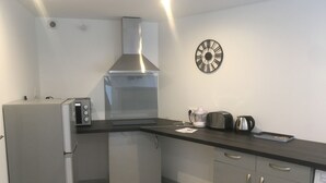 Une cuisine compacte équipée d’un réfrigérateur, d’une cuisinière, d’un grille-pain et d’une bouilloire.