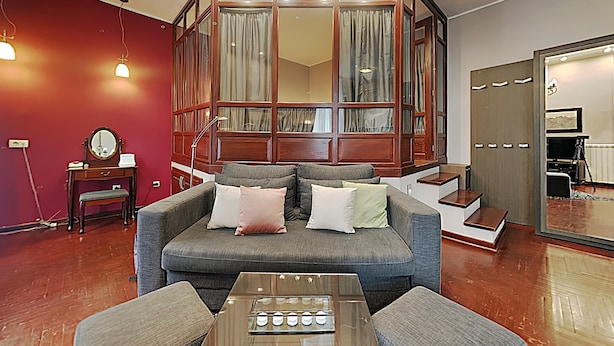 Un salon moderne avec un canapé gris, un meuble en bois agrémenté de rideaux, un miroir et une table basse.