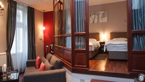 Une chambre d’hôtel avec un canapé, un lit, une table de chevet, une lampe et un miroir.