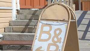 Een houten gebouw met een bruine deur en een bord waarop 