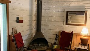 A rustic interior with a stone fireplace, wooden flooring, and two rocking chairs. - Rustic River Cabin under the Oaks and just a short walk to the river. (Uvalde)