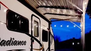 A covered RV with the word "Radiance" on the side, a decorative door, and a paved entrance area.