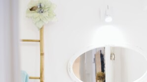 Un bagno con lavandino bianco, specchio e porta asciugamani con due asciugamani.