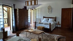 A bedroom with a bed, wooden furniture, a hanging light fixture, and a view through an open door. - Chambre d'Hôtes La Bastide de Villenave (Villenave)