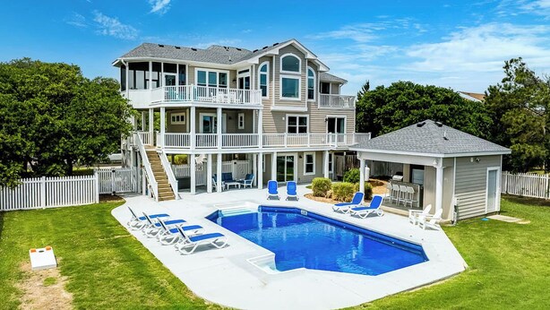 Une maison à deux étages avec une grande piscine, un patio couvert et une cour clôturée.