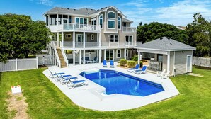 Une maison à deux étages avec une piscine, un patio couvert et une cour clôturée.