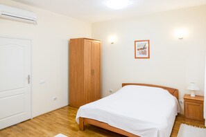 A bedroom with a wooden bed, a wardrobe, and a wall-mounted light fixture.