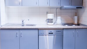 Uma cozinha moderna com armários cinza, uma máquina de lavar louça, uma cafeteira e uma chaleira.