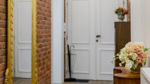 Una habitación con pared de ladrillo, puerta blanca y armario de madera con un florero.