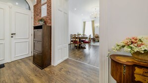 A hallway with a wooden cabinet, a dining area with a chandelier, and a flower arrangement. - Royal Apartment Zagreb (Zagreb)
