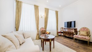 A living room with a sofa, a coffee table with fruit, a TV, and a wooden cabinet. - Royal Apartment Zagreb (Zagreb)