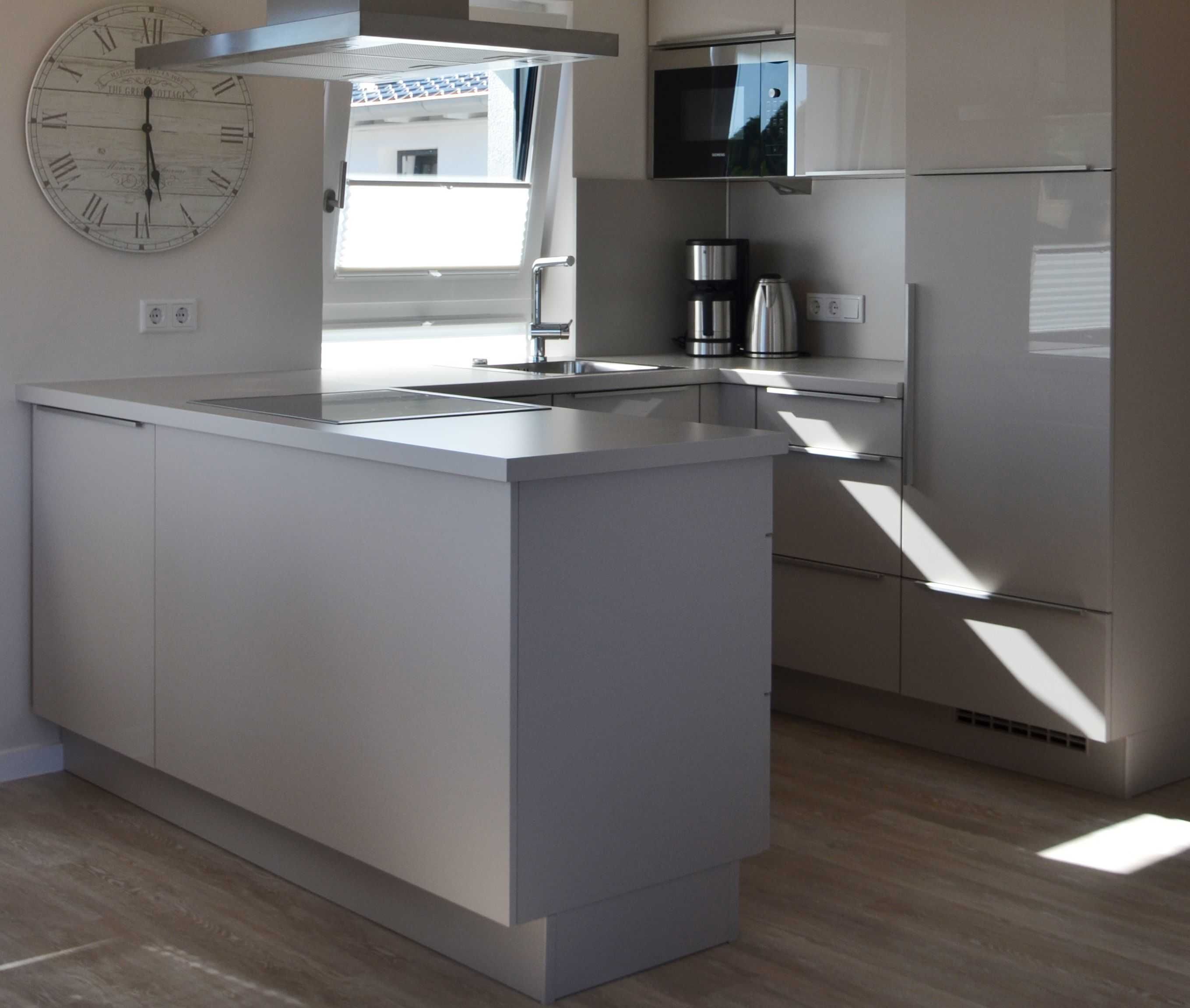 A modern kitchen with a central island, stainless steel appliances, and a large clock on the wall.